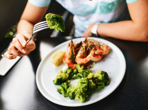 Woman Eating Grilled Broccoli with King Prawns